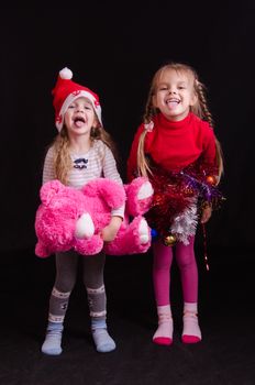 Two girls of five and three years in a New Year dress on a black background