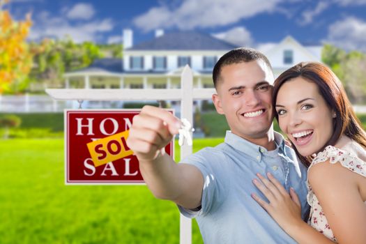 Mixed Race Excited Military Couple In Front of New Home with New House Keys and Sold Real Estate Sign Outside.