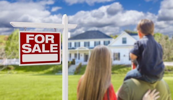 Curious Family Facing For Sale Real Estate Sign and Beautiful New House.