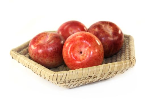 red, raw pluots in front of white background