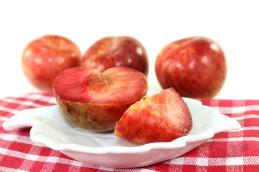 red, raw pluots in front of white background
