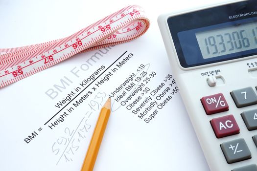 measuring tape, a calculator and a paper with a Body mass index formula