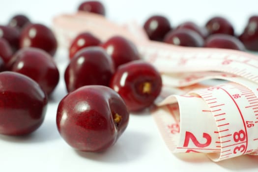 Fruit diet. Cherries with measuring tape on white background