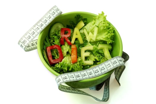 Green plate with word diet composed of slices of different vegetables on salad