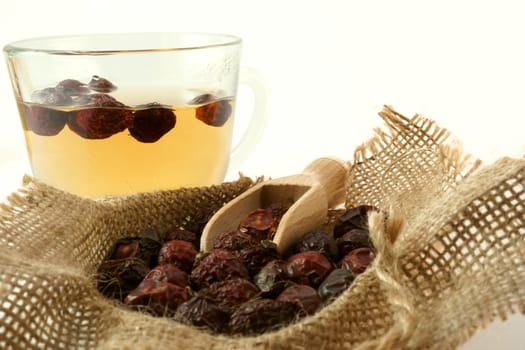 Herbal medicine. Cup of herbal tea with dried rose hips in a sack