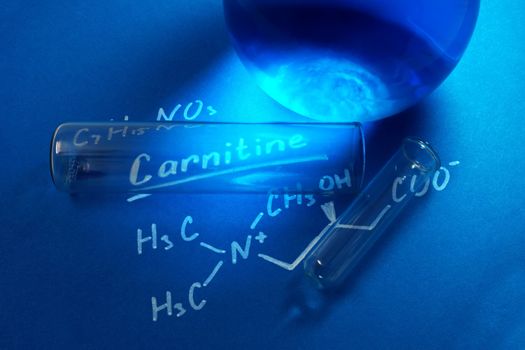 the chemical formula of carnitine with test tubes on the blue background