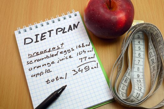 Diet plan. Measuring tape, a marker and a notepad with a daily diet plan