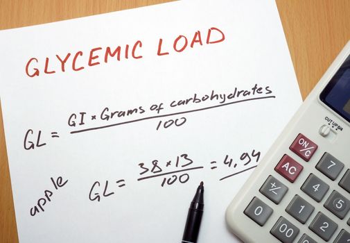 calculator, a marker and a paper with a glycemic load formula