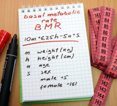 Measuring tape, a marker and a notepad with a calculation of bmr. Basal metabolic rate