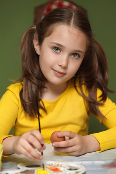 Girl painted Easter eggs at the table