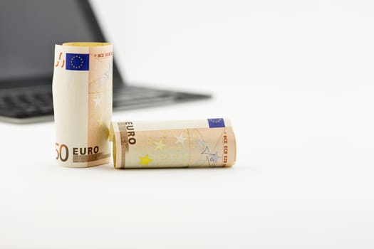 Focus on Euro currency  in front of tablet and keyboard.  Selective focus on money with copy space to right. 