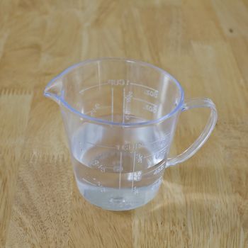 warm water in measuring cup on a wood background