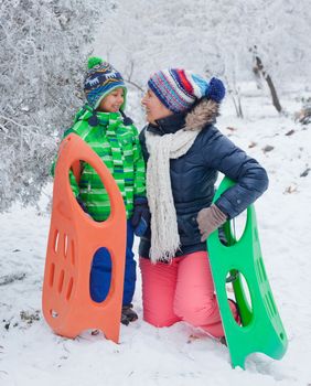 Winter, play, fun - Mother and her cute little son having fun with sled in winter park