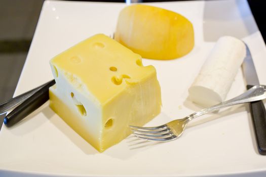 3 kinds of Cheese with knife and fork on white cutting board