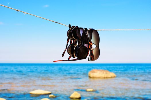 Sunglasses hanging on a rope on a seashore