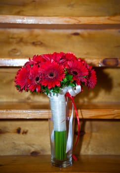 Fresh red bouquet with ribbon and bow over wooden background.
