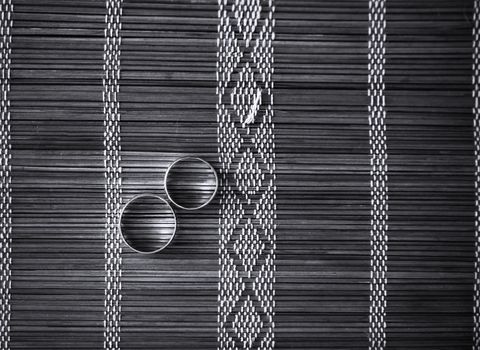 Two wedding rings on bamboo mat. Black and white photo.