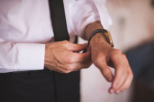 men putting on hand watch wearing shirt