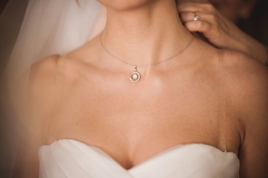 bride being helped putting on white gold necklace