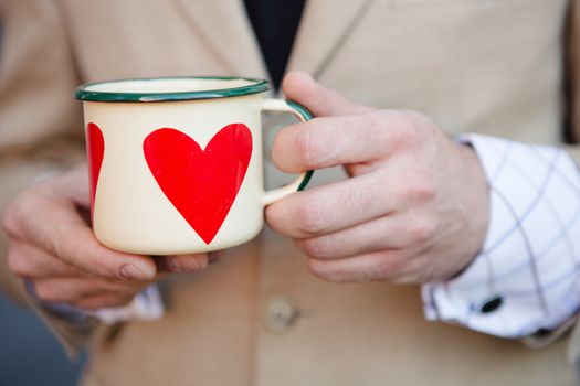 woman holding hot cup of coffee with heart