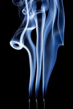 delicate smoke plumes, puffs and eddies  from  burning incense sticks