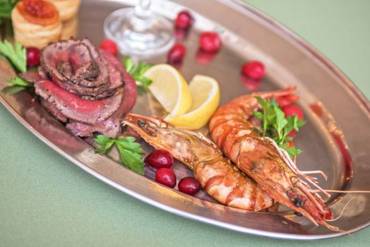 Grilled shrimps and beef meat on a plate