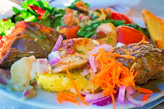 On the table on a platter lies stews and side dishes from a variety of vegetables: carrots, onions, lettuce, tomatoes.