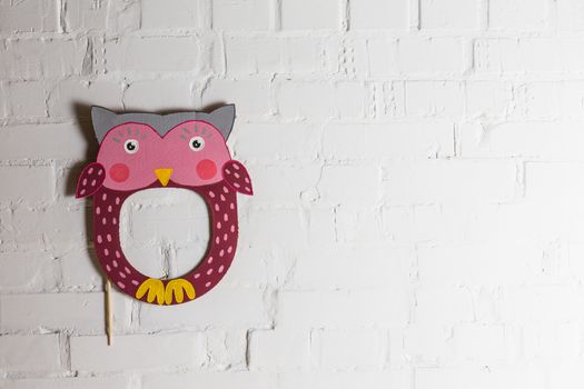 Bright cardboard mask on a white brick wall. Consept card. Owl