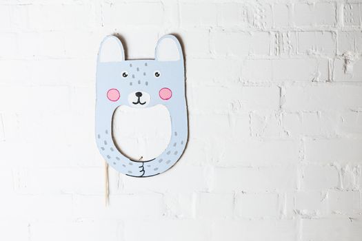 Bright cardboard mask on a white brick wall. Consept card. Rabbit