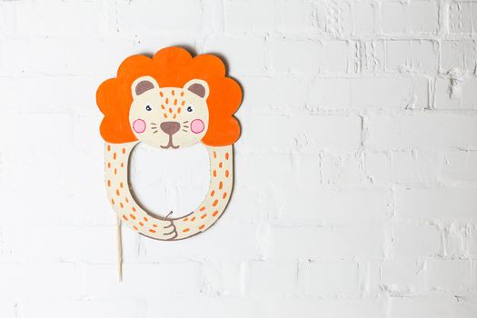Bright cardboard mask on a white brick wall. Consept card. Lion