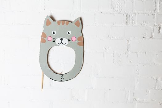 Bright cardboard mask on a white brick wall. Consept card. Cat