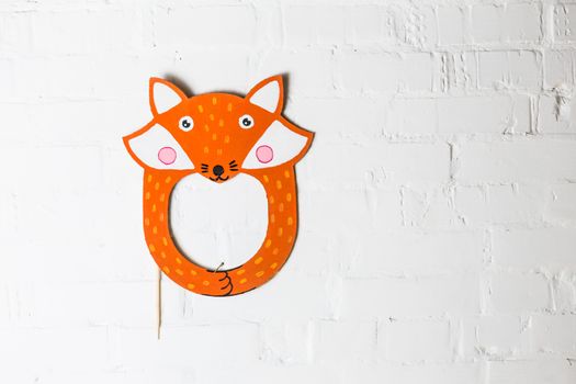 Bright cardboard mask on a white brick wall. Consept card. Fox