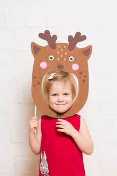 Little blonde girls holding deer mask on white background