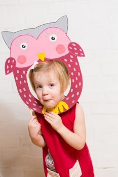 Little blonde girls holding owl mask on white background