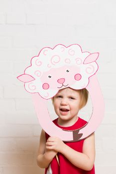 Little blonde girls holding sheep mask on white background