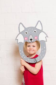 Little blonde girls holding wolf mask on white background