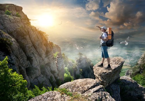 Tourist on the top of a rock at sunrise