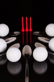 Teaspoons and golf equipments on the black glass desk
