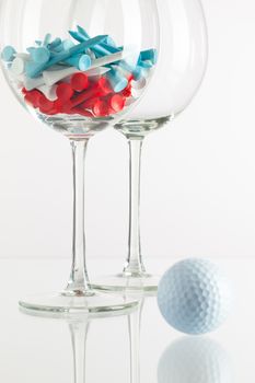 Two glasses of wine and golf equipments on the glass desk