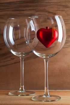 Two glasses  of wine and red heart on the wooden background from real wood veneer with interesting growth
