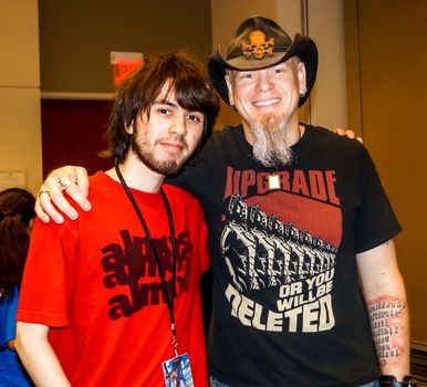 Raleigh, NC, USA - May 24, 2014: Animazement 2014 anime convention attendee poses with singer/songwriter/voice actor Jason Charles Miller at the Raleigh Convention Center on May 24, 2014, in Raleigh, North Carolina