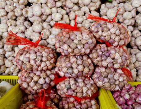 Lots of white purple Italian garlic bulbs on display for sale at an outdoor farmers market