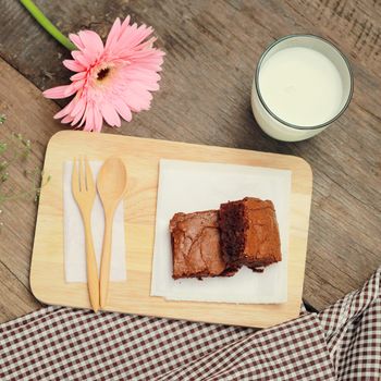 Tasty brownies with glass of milk and flower, retro filter effect 