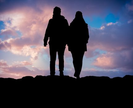 Silhouette Of A Couple Hiking On A Mountain Against Beautiful Sunset