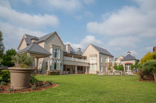 The back garden of a big double story house, build in a French Country style.