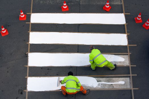 workers painting crosswalk with white colour - view from above