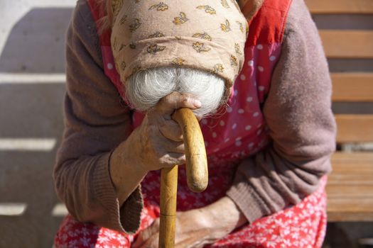 old peasant woman sitting leaning on a walking stick