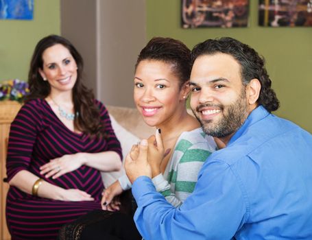 Smiling Hispanic couple sitting with beautiful surrogate mother