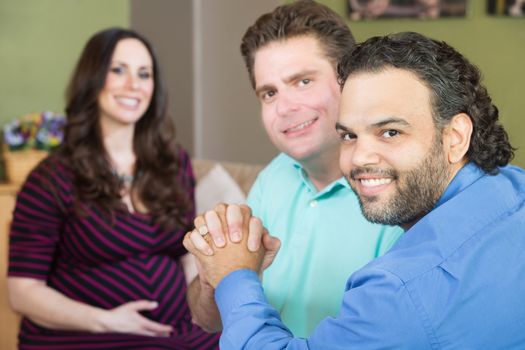 Handsome gay men holding hands with smiling surrogate mother