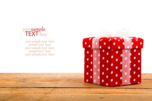 red gift box, polka dots, on wood background, isolated in white